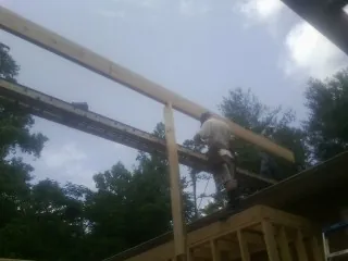 Carpenter setting a ridge beam over a new addition frame — Ice Dam Removal by Roofing Brothers in West Newfield