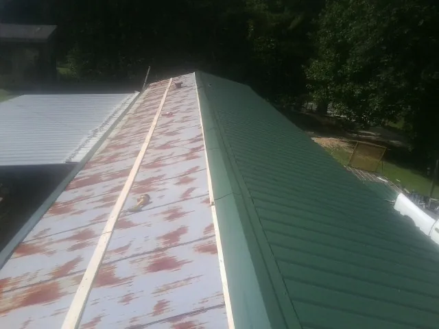 Old rusted panels beside newly installed green metal roofing — Wind Damage Roof Repair by Roofing Brothers in West Newfield