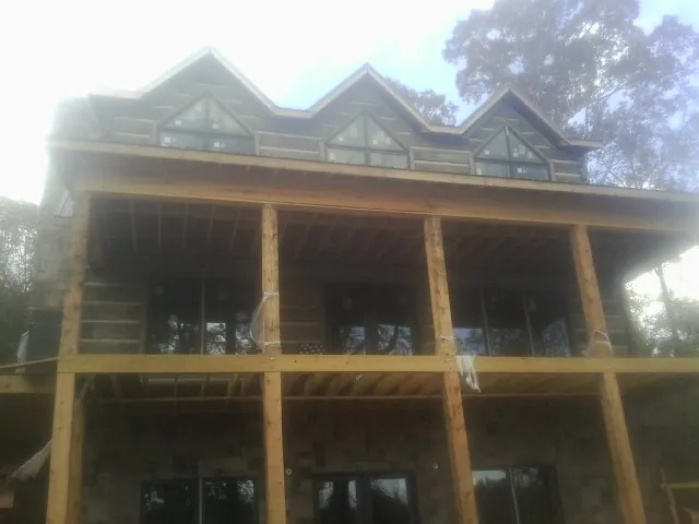 Dormers and porch framing on a large log home under construction — Roof Coating work by our crew in West Newfield