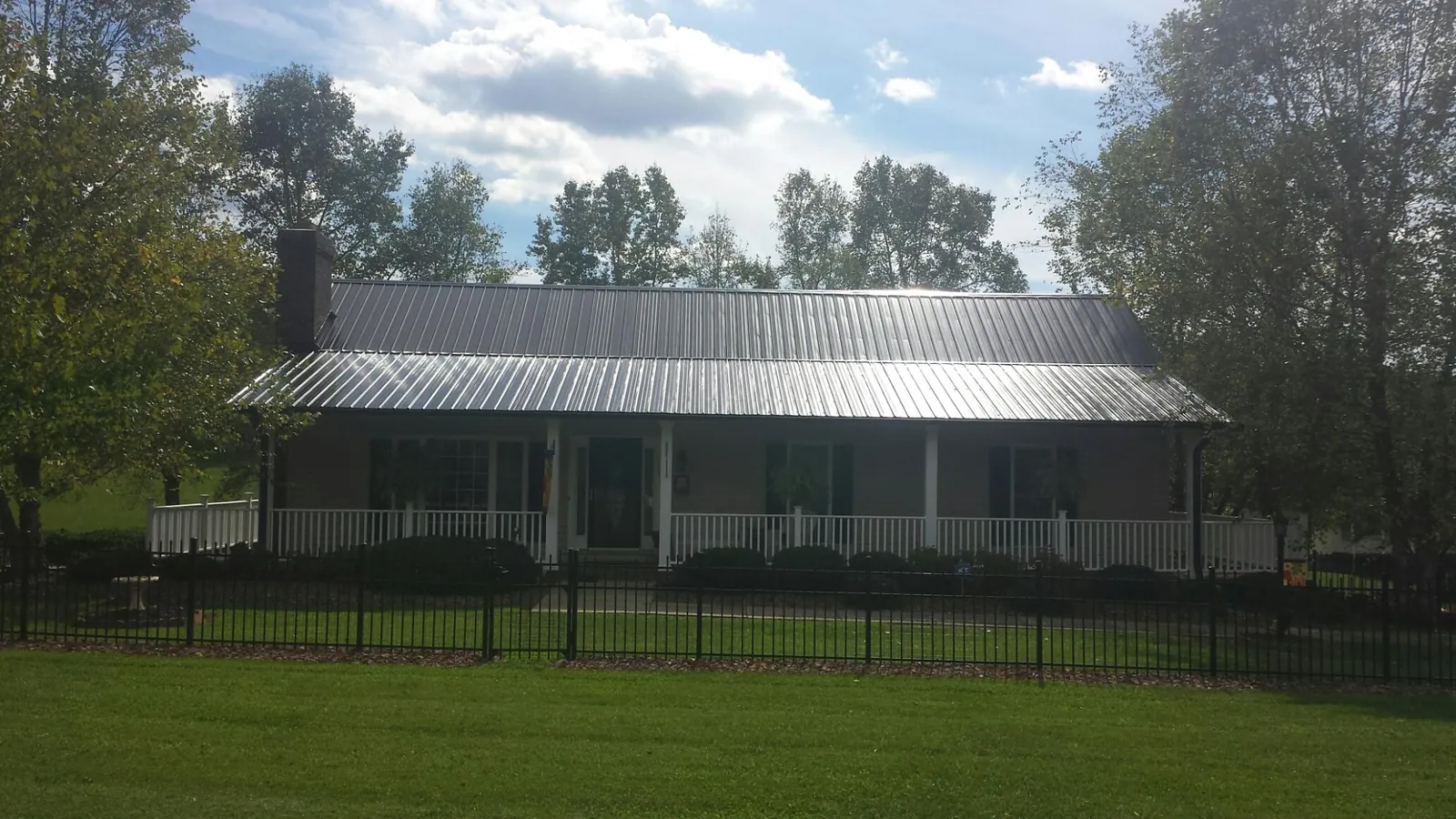 Gray metal roof on a brick ranch with a full width front porch — Gutter Guard Installation work by our crew in West Newfield