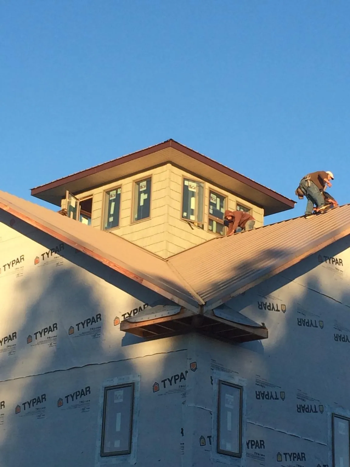 Roofers working around a rooftop cupola on a new metal roof at sunset — Roof Waterproofing in West Newfield by Roofing Brothers